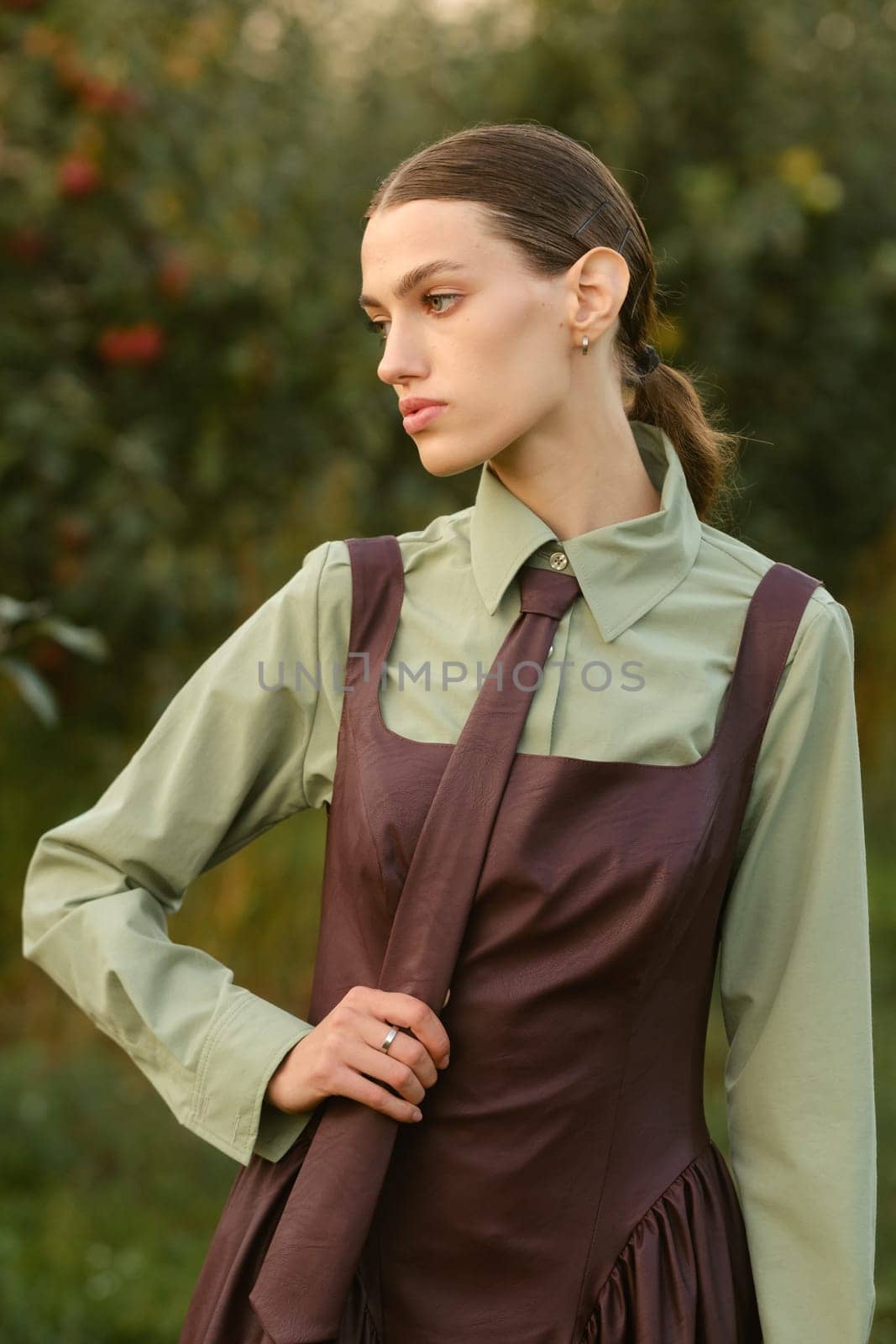 A stylish girl in a dress with a tie in a summer garden. A fashion show in nature.