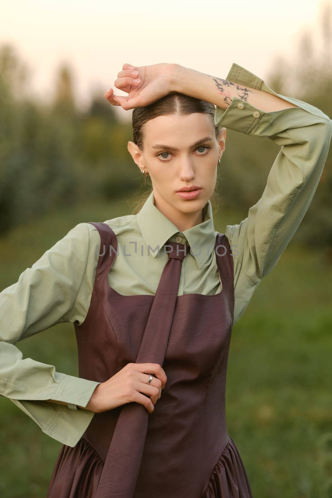 A stylish girl in a dress with a tie in a summer garden. A fashion show in nature.