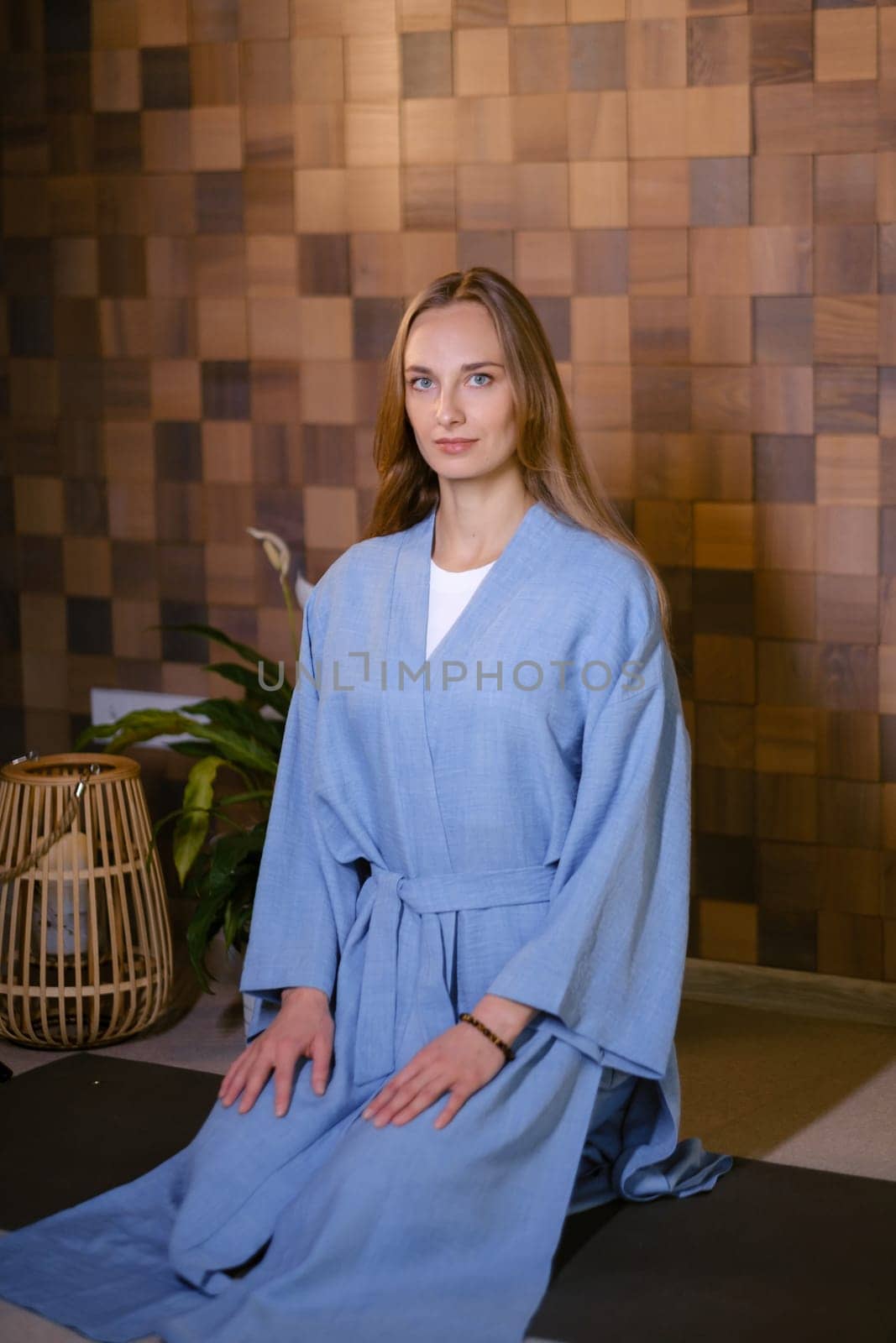 Girl in blue kimano practicing kundalini or qigong yoga in fitness gym . Spiritual energy, life force located at the base of the spine.