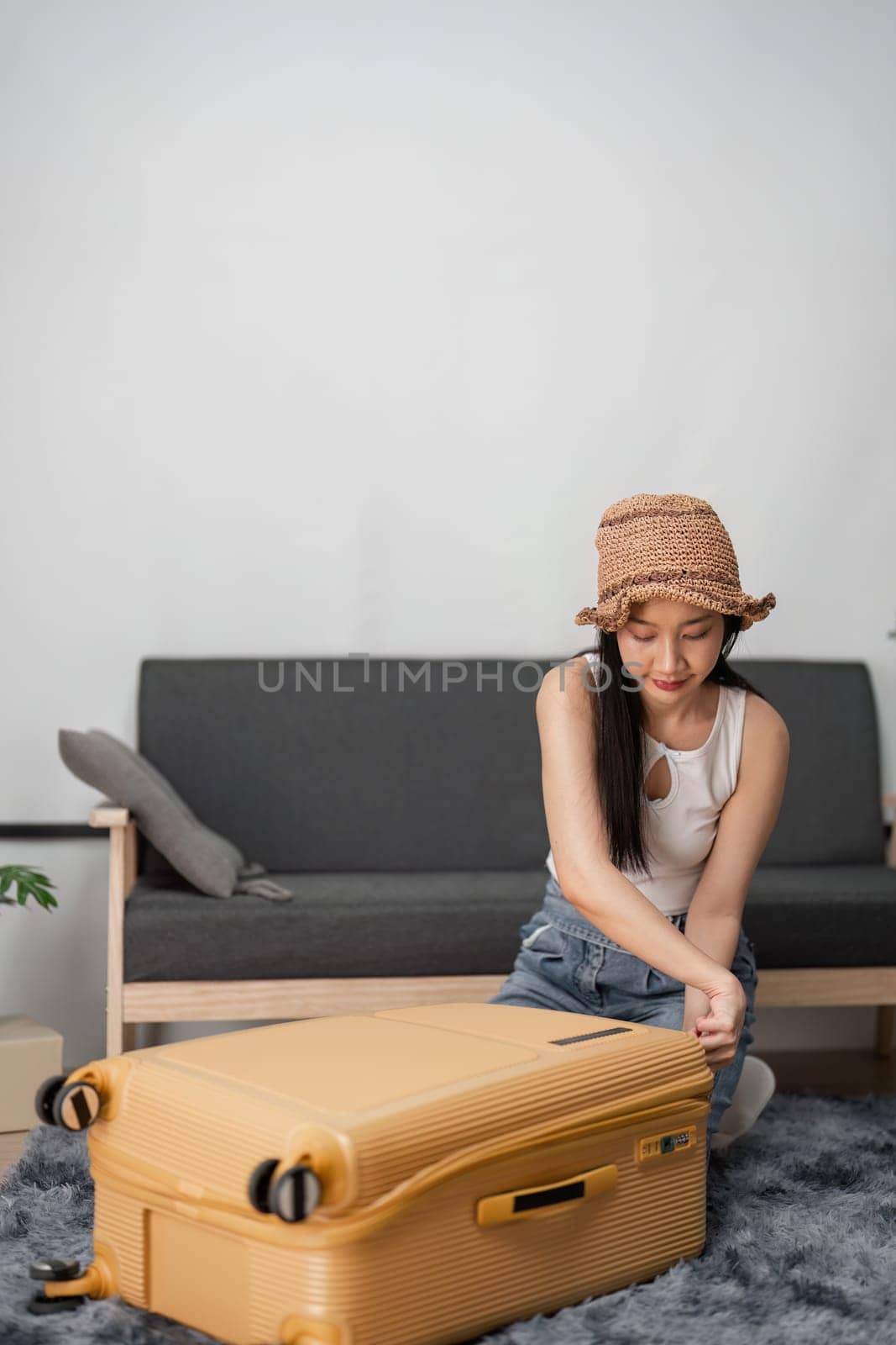 A young woman prepares for her journey, packing a suitcase in a stylish living room, ready for her travel adventure.