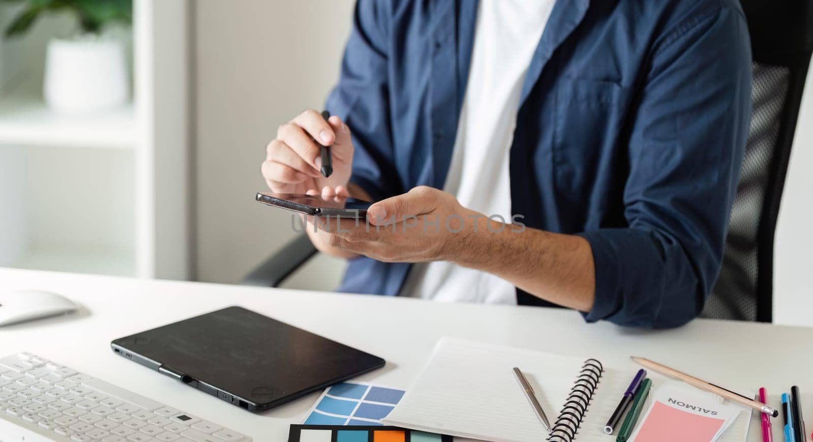 Graphic designer in a contemporary studio setting, using digital tools and color swatches for creative projects.
