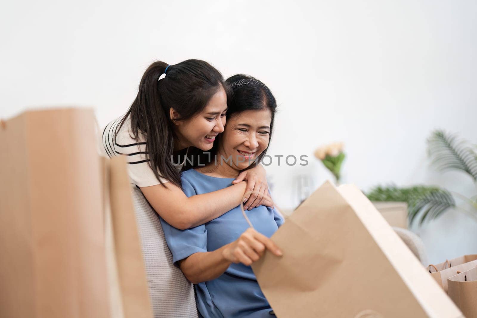 A joyful mother and child bonding over shopping, holding paper bags and smiling at home.