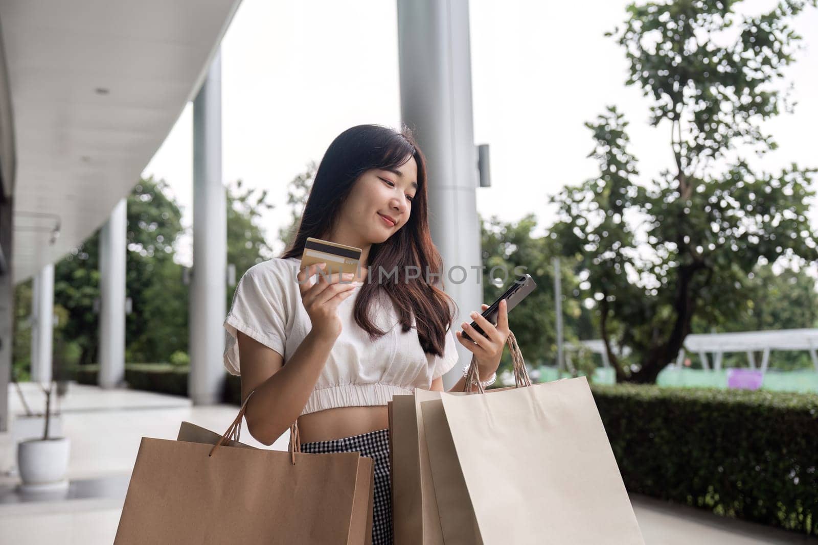A young woman enjoys Black Friday shopping, holding bags and a credit card, symbolizing retail excitement and holiday deals.