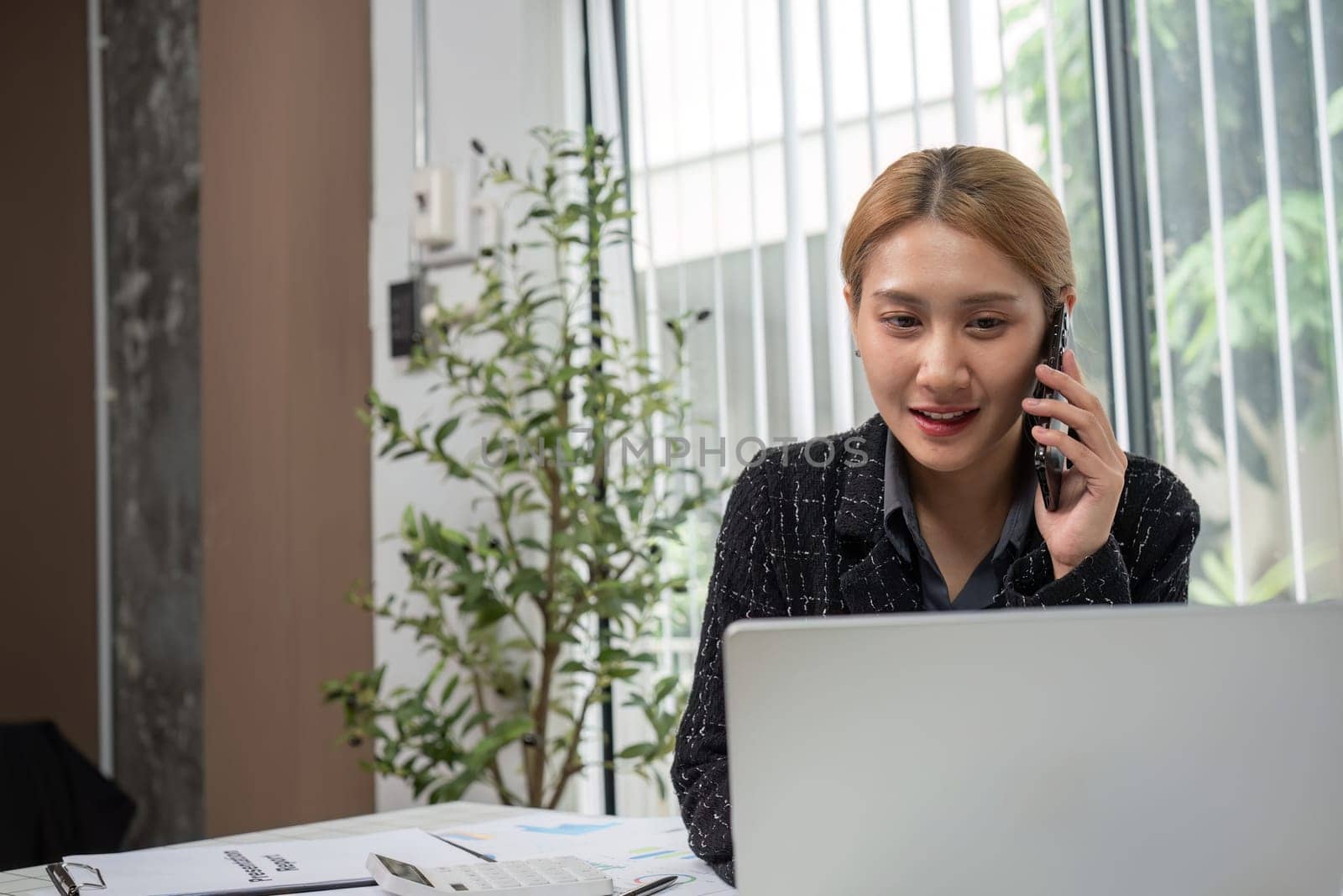 Businesswoman in office analyzing graphs on a laptop, focusing on financial data for strategic planning.