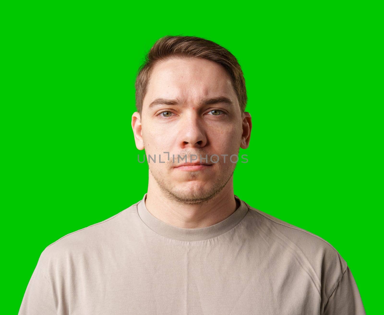 A man standing against a vibrant green backdrop with neutral expression close up