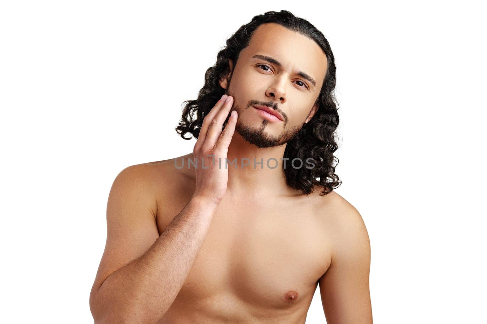 Young man with curly hair thoughtfully posing against a plain background in a studio setting