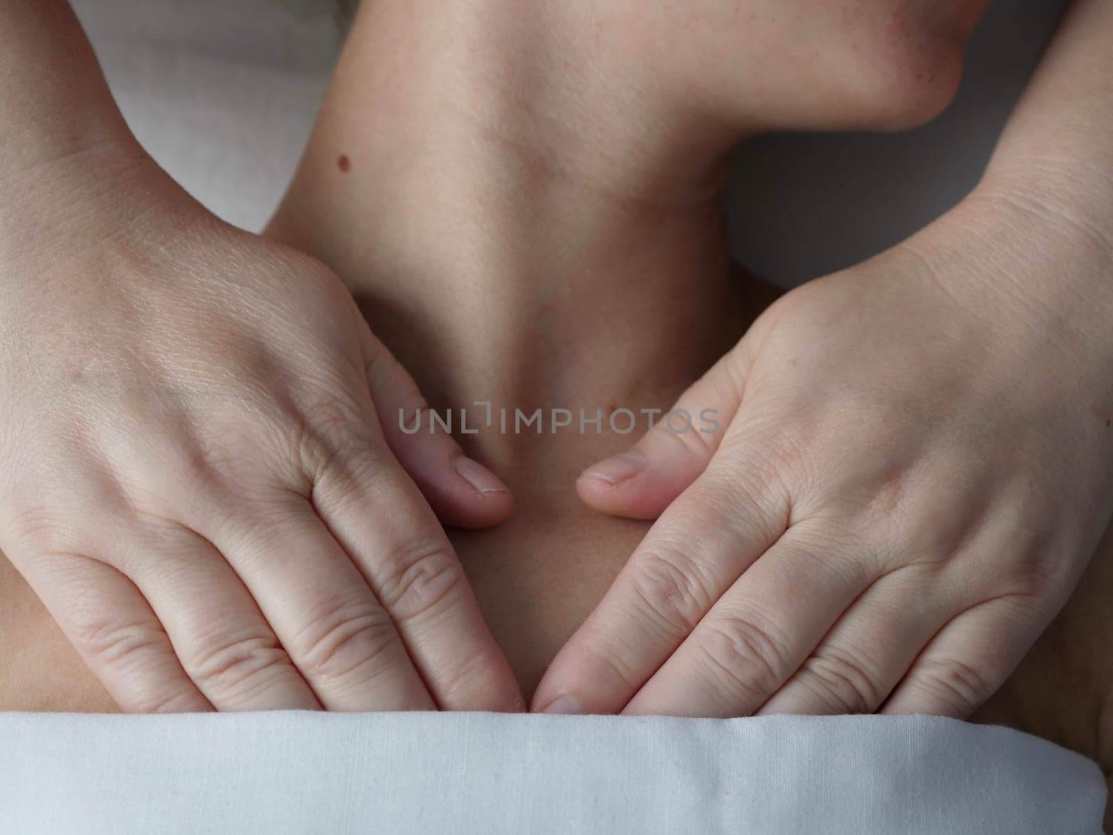 The masseur massages the client in the thoracic area of the collarbone. Close-up, no face