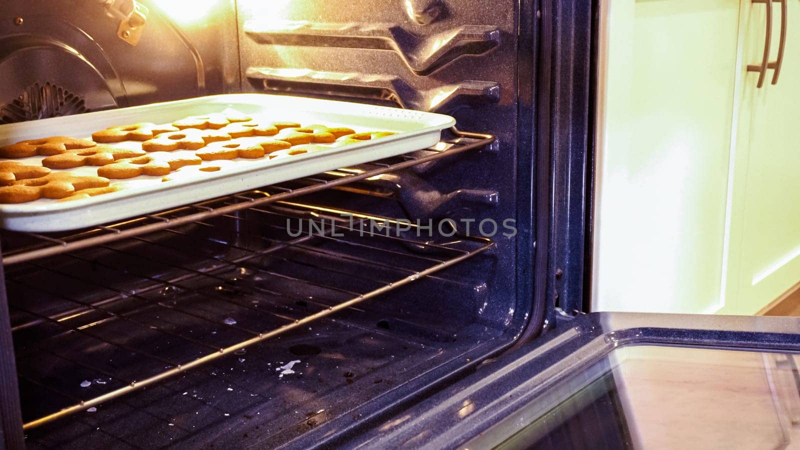 Scrumptious gingerbread cookies getting baked to perfection in a gas oven, filling the kitchen with warm, aromatic holiday bliss.