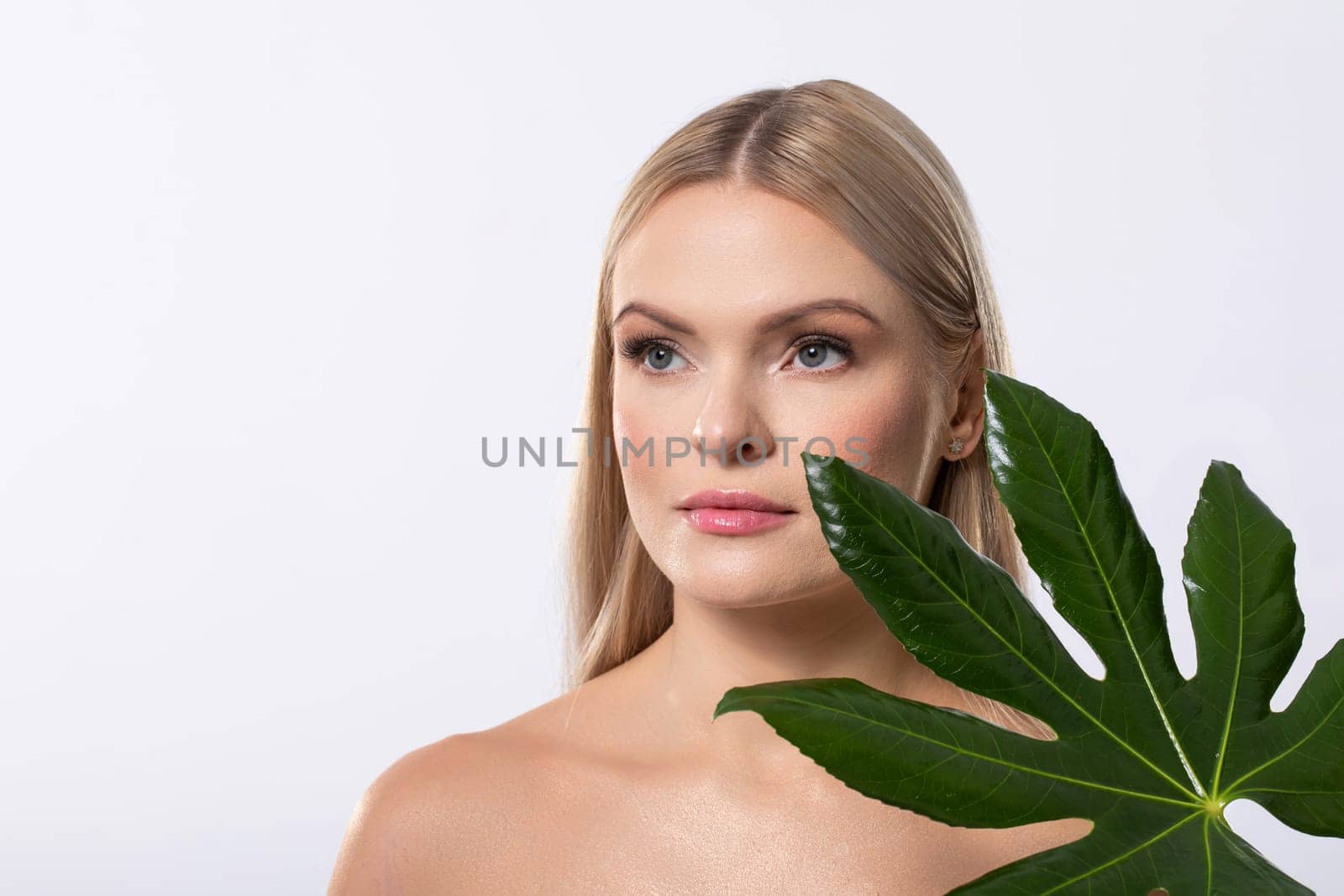 A serene portrait of a stunning model surrounded by lush green leaves, exuding natural beauty and elegance