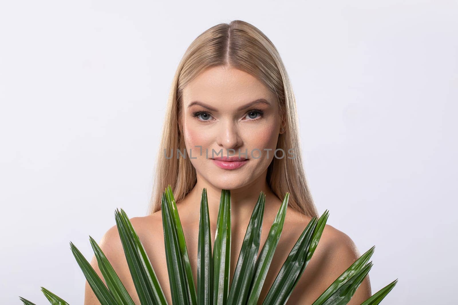 A stunning model with long hair holds vibrant green plants, beautifully embodying nature and harmony