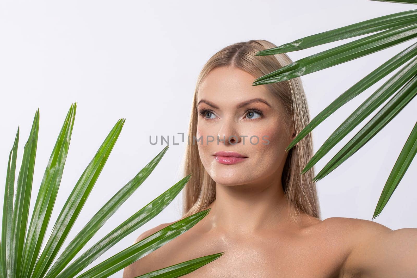 A radiant beauty unfolds in an enchanting natural setting, showcasing shimmering skin alongside lush tropical foliage