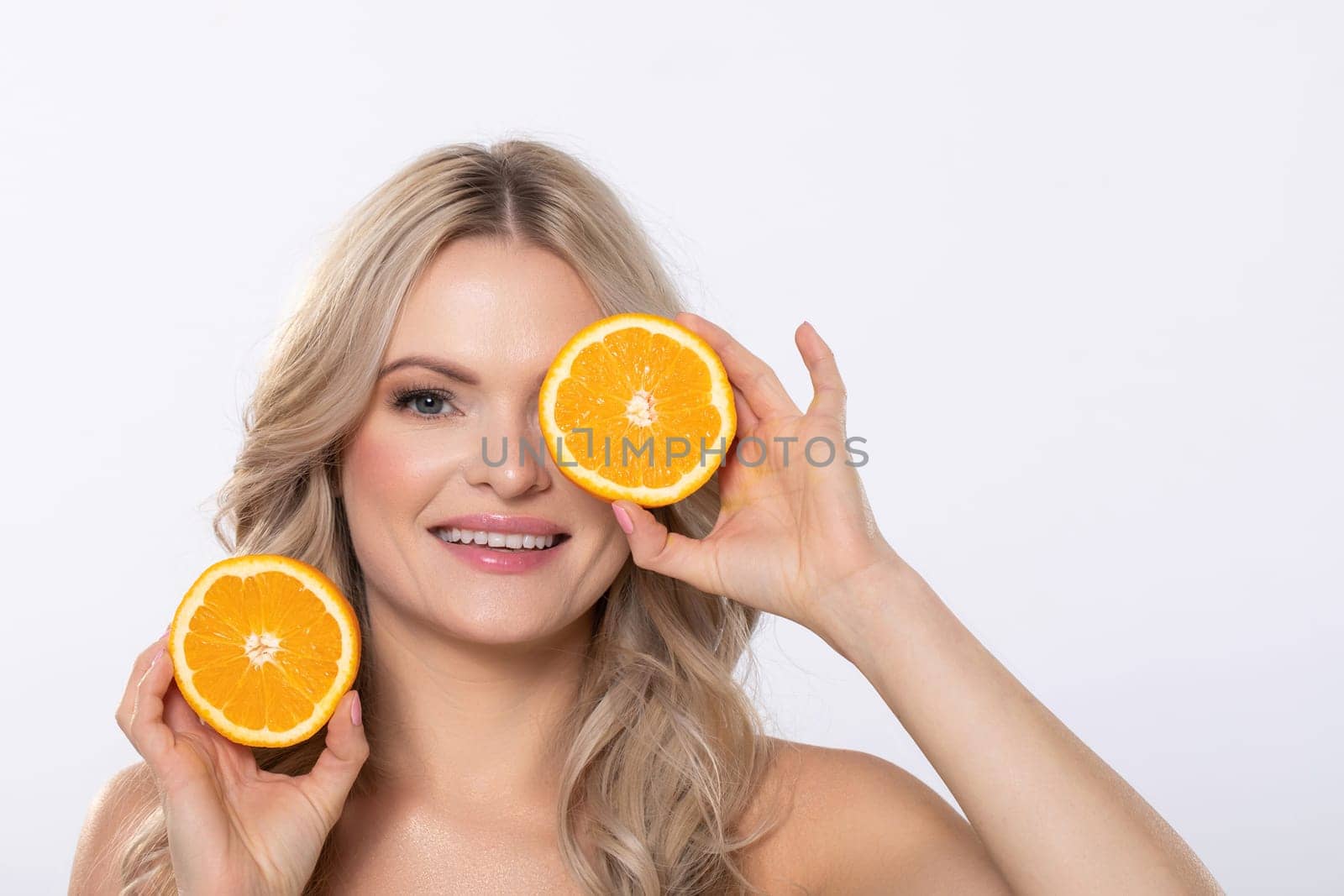 A cheerful woman happily poses with fresh orange halves in her hands, promoting a healthy and vibrant lifestyle