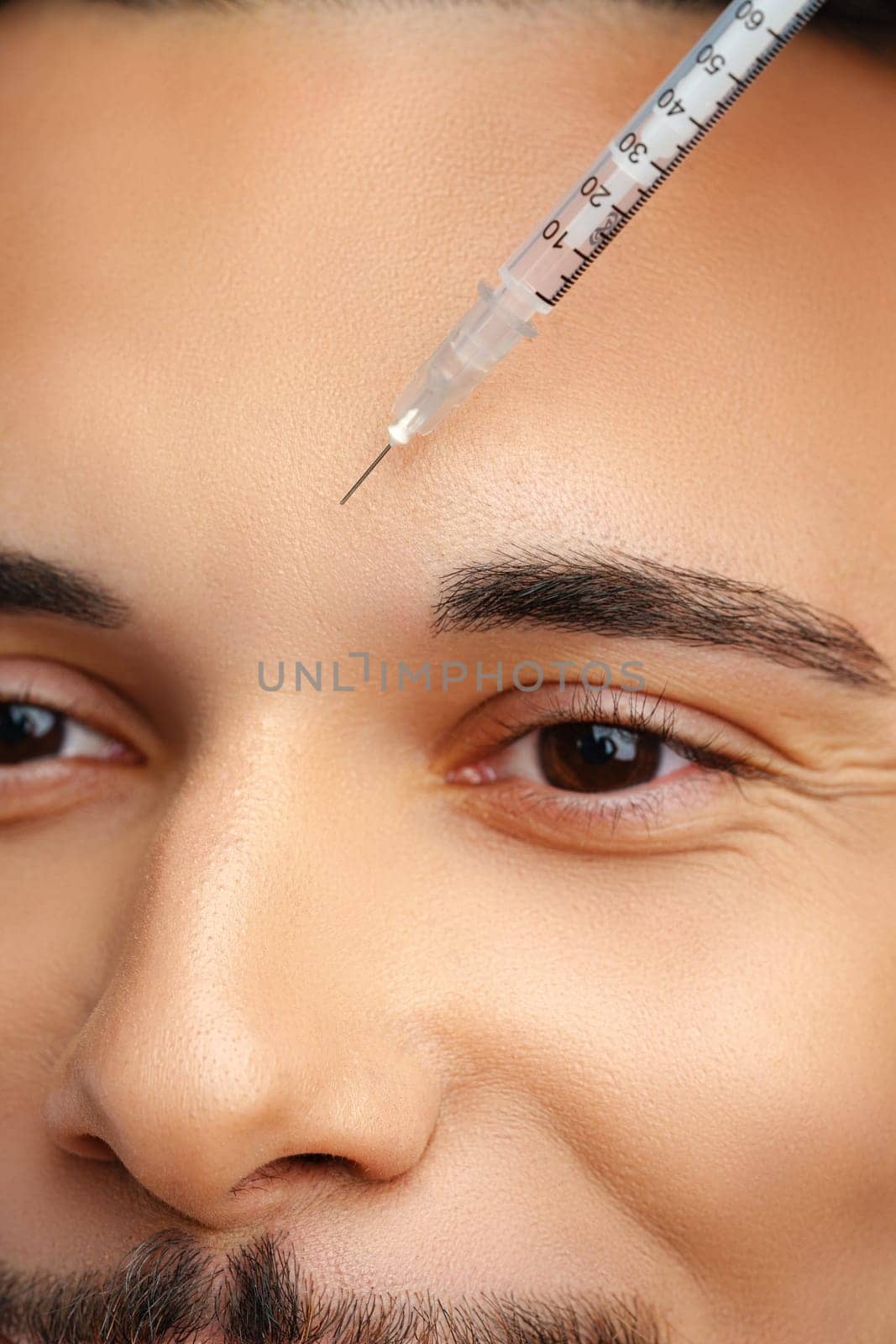 Man receiving facial treatment with a syringe for enhancing appearance, likely in a modern clinic