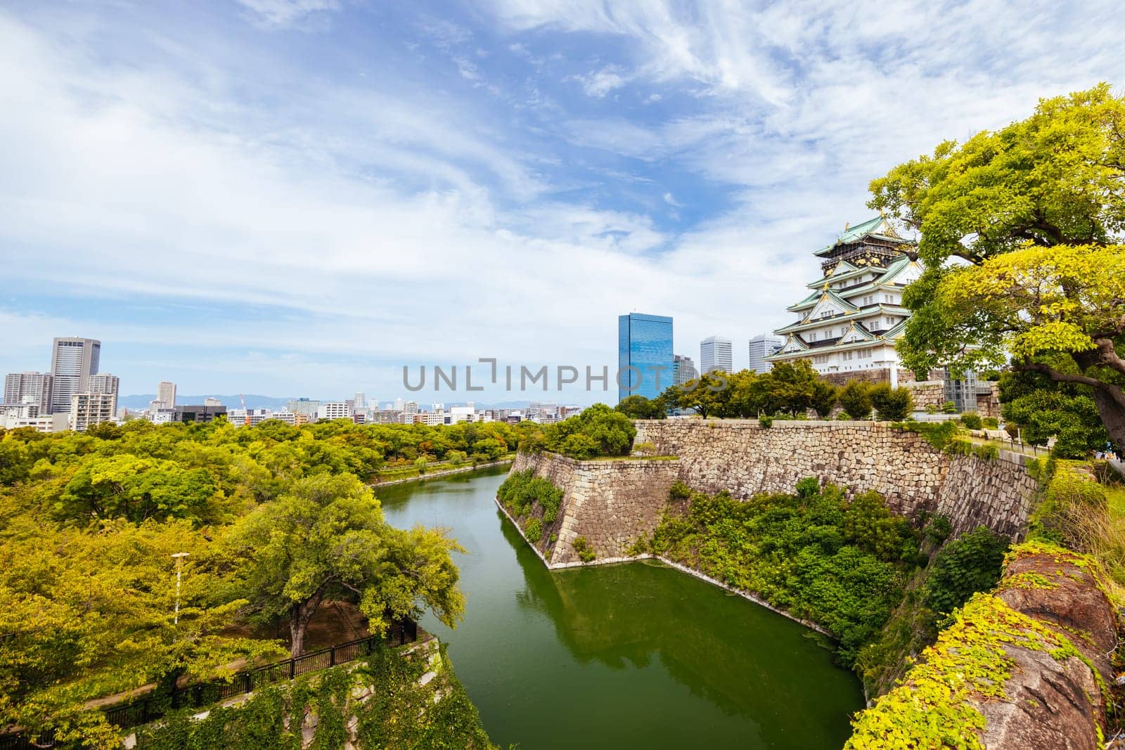 OSAKA, JAPAN - SEPTEMBER 25 2024: The iconic Osaka Castle and surrounding moat and gardens on a warm clear autumn day in Osaka, Japan on September 25th 2024