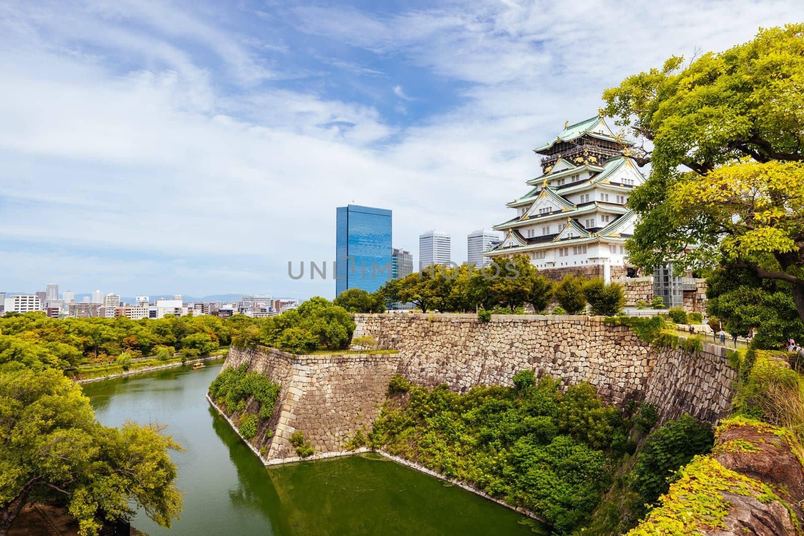 OSAKA, JAPAN - SEPTEMBER 25 2024: The iconic Osaka Castle and surrounding moat and gardens on a warm clear autumn day in Osaka, Japan on September 25th 2024