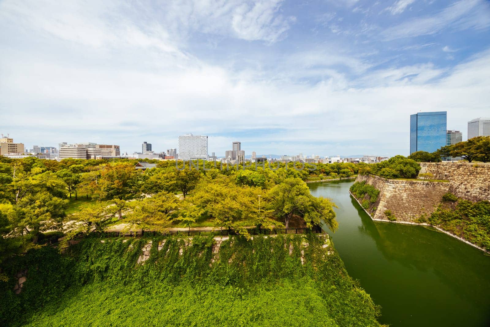 OSAKA, JAPAN - SEPTEMBER 25 2024: The iconic Osaka Castle and surrounding moat and gardens on a warm clear autumn day in Osaka, Japan on September 25th 2024
