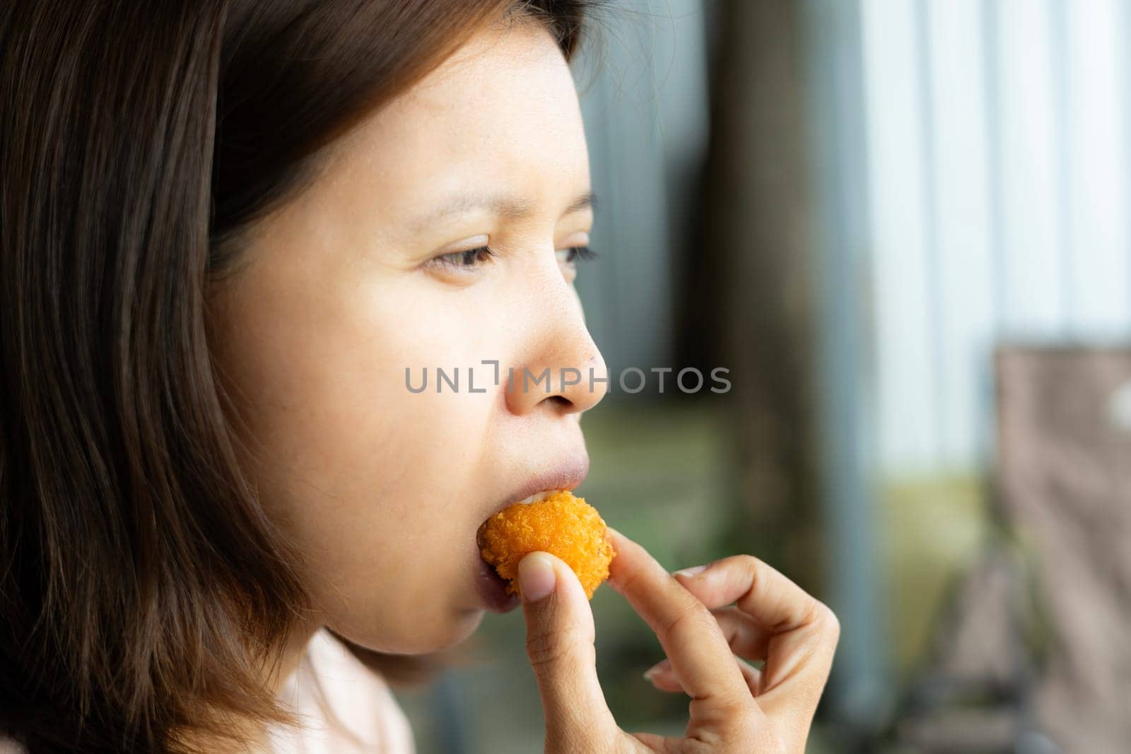 Woman bites into a crispy fried cheese ball.
