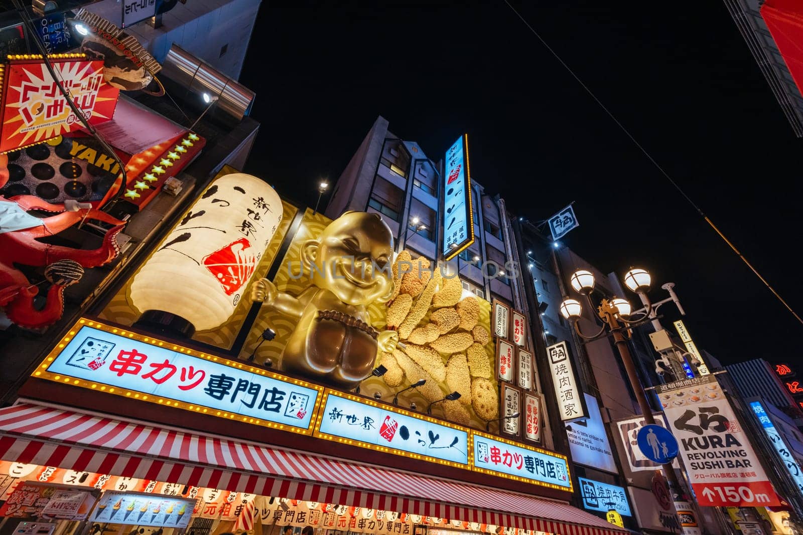 OSAKA, JAPAN - SEPTEMBER 24 2024: Osaka's famous Dotonbori area with many restaurants and iconic food signage, including this golden baby in Osaka, Japan