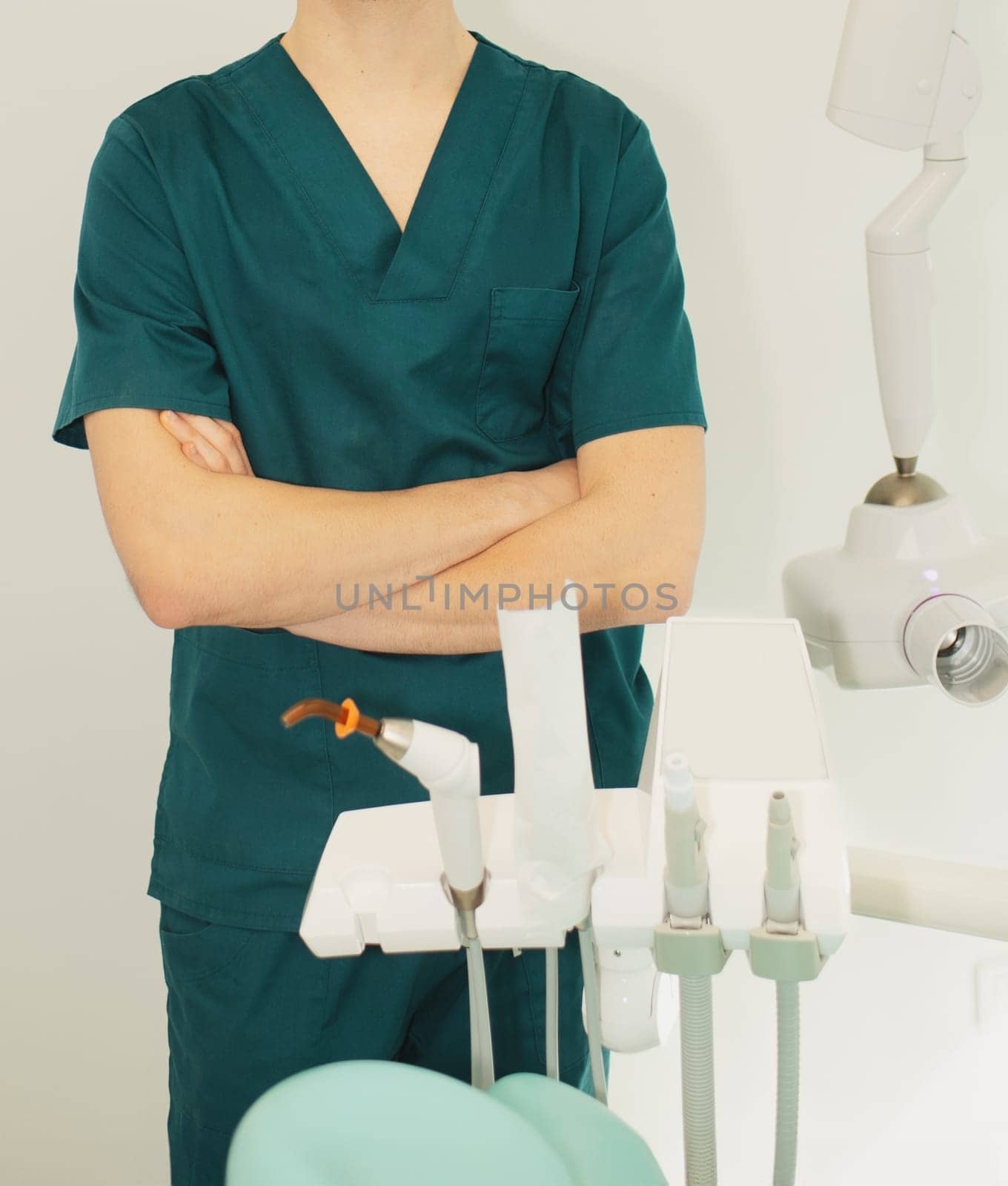 Dentist man in office near chair with dental tools