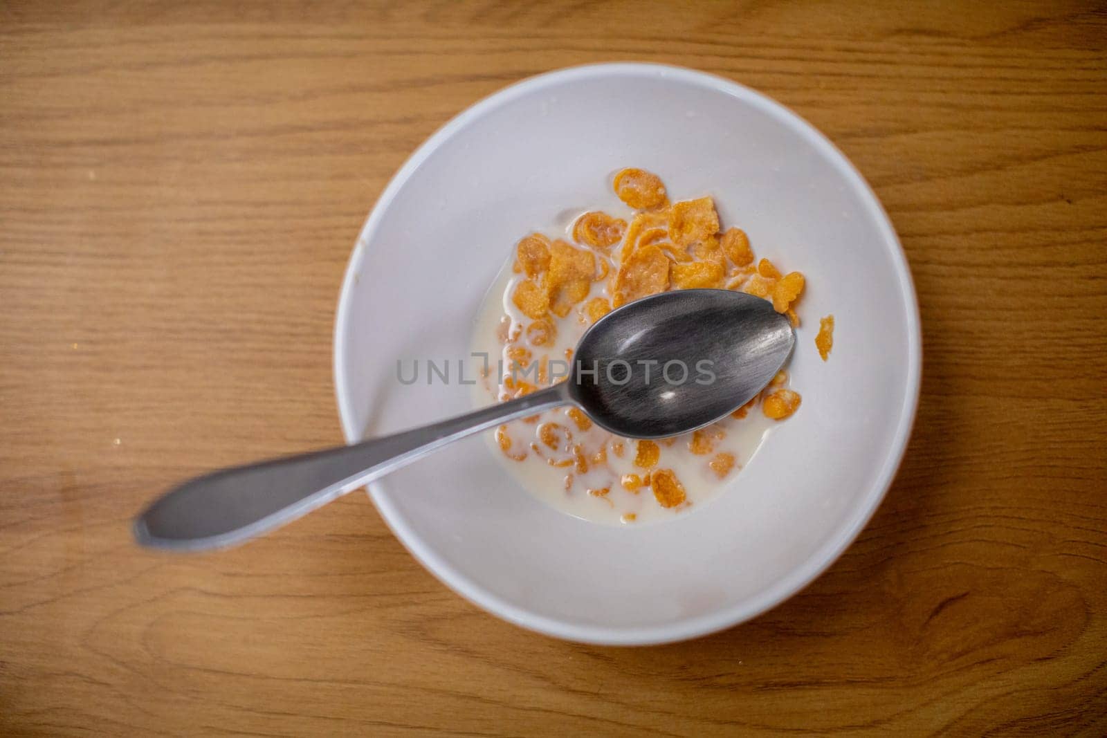 This image offers a closeup view of a vibrant bowl filled with colorful cereal alongside a spoon on a wooden surface