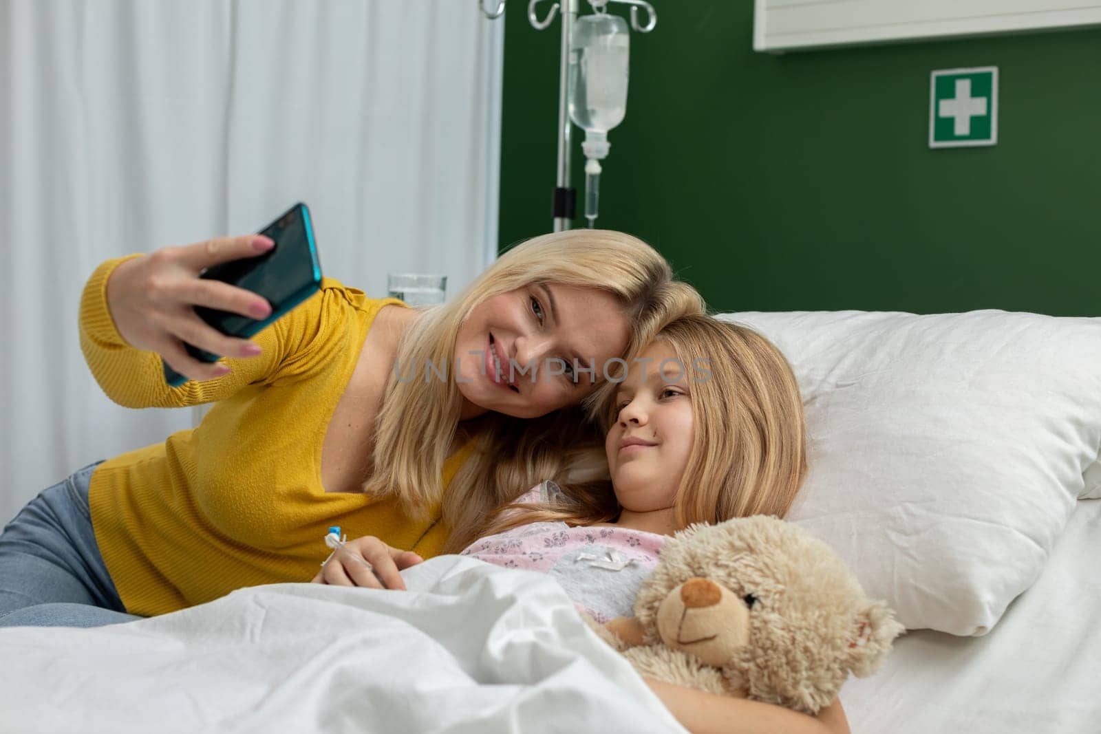 A heartwarming and touching moment captured as a mother and daughter share a selfie in a cozy hospital room