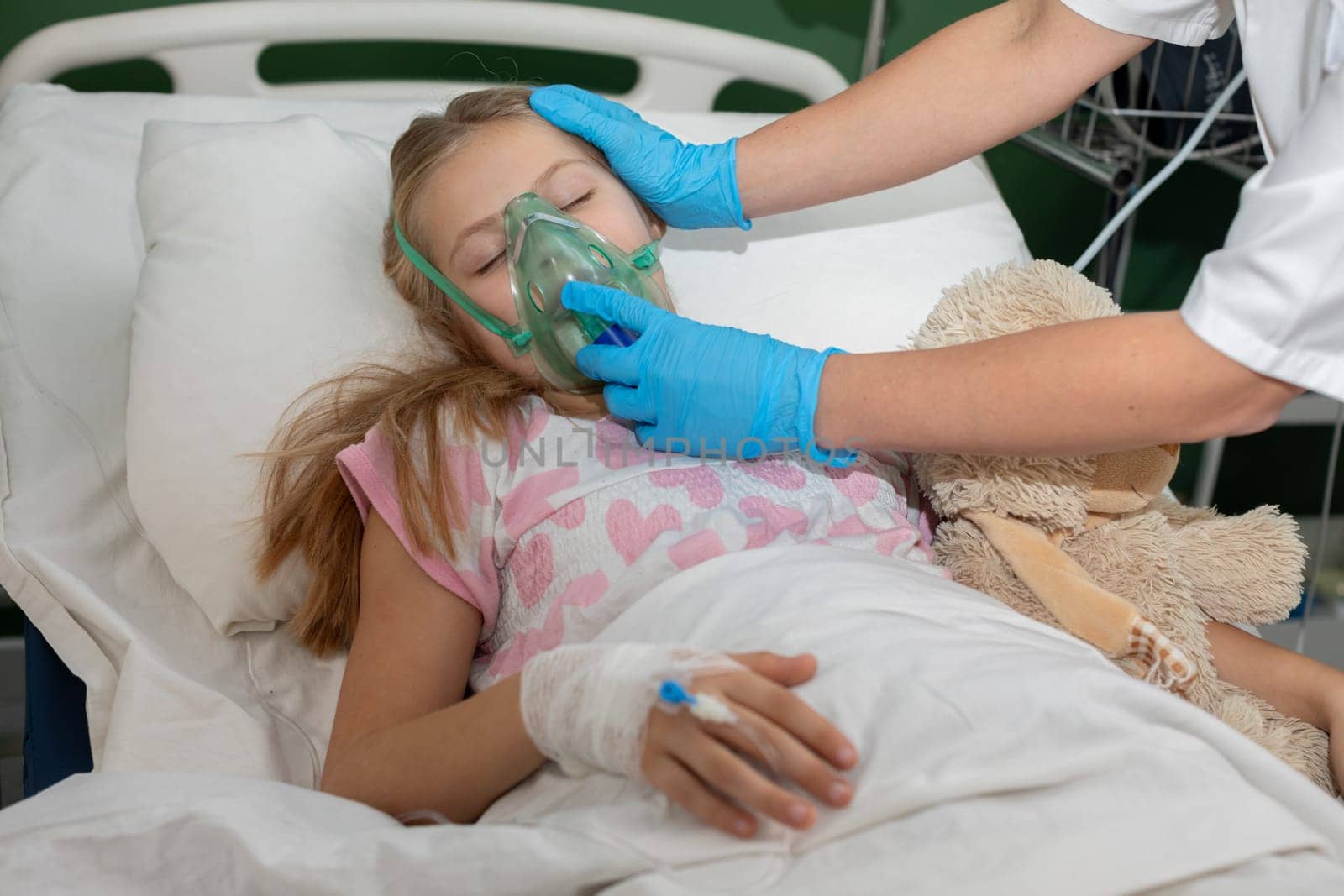 A young girl lying in a hospital bed is receiving vital oxygen therapy with a gentle, caring hand resting on her head