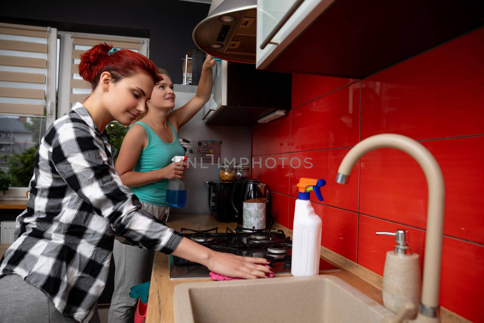 A group of friends are happily enjoying cooking together in a modern kitchen that is filled with vibrant colors