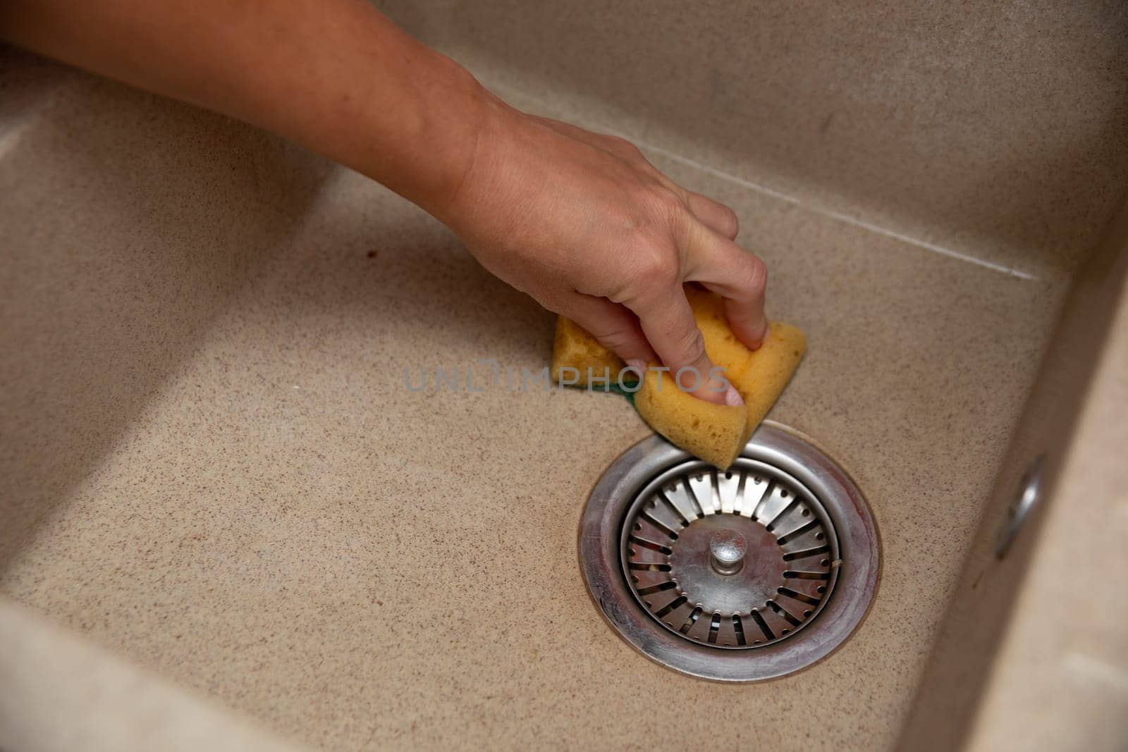 A person vigorously cleaning a kitchen sink with a sponge, promoting hygiene and overall cleanliness