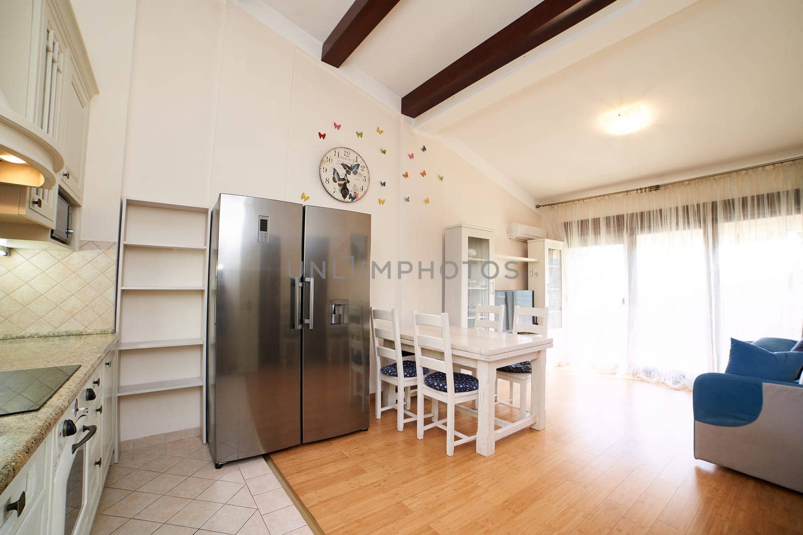 Kitchen studio with double-door refrigerator, table, chairs, sofa and cabinets. High quality photo