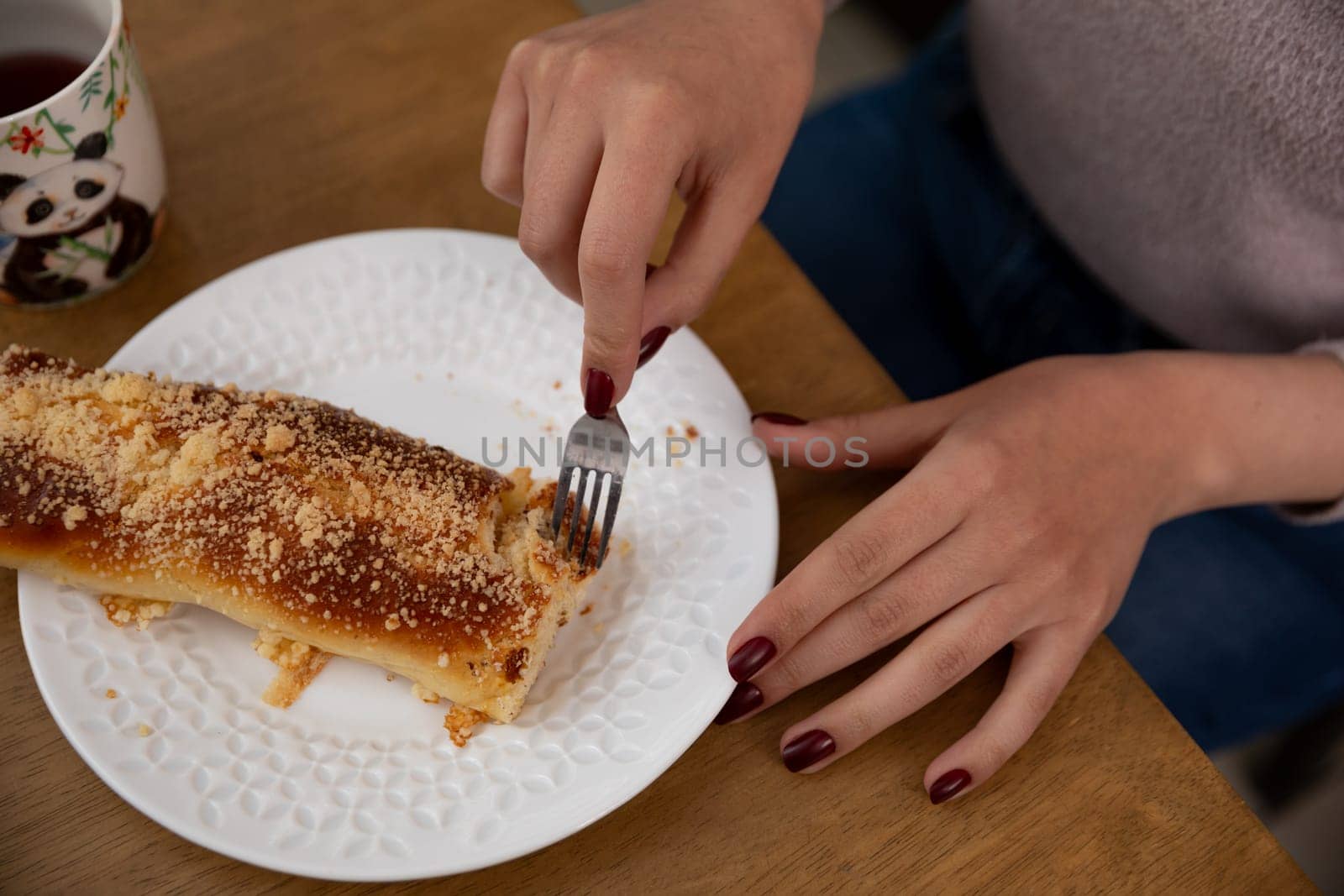A warm and cozy image depicts a person delightfully enjoying a delicious pastry with tea on a wooden table