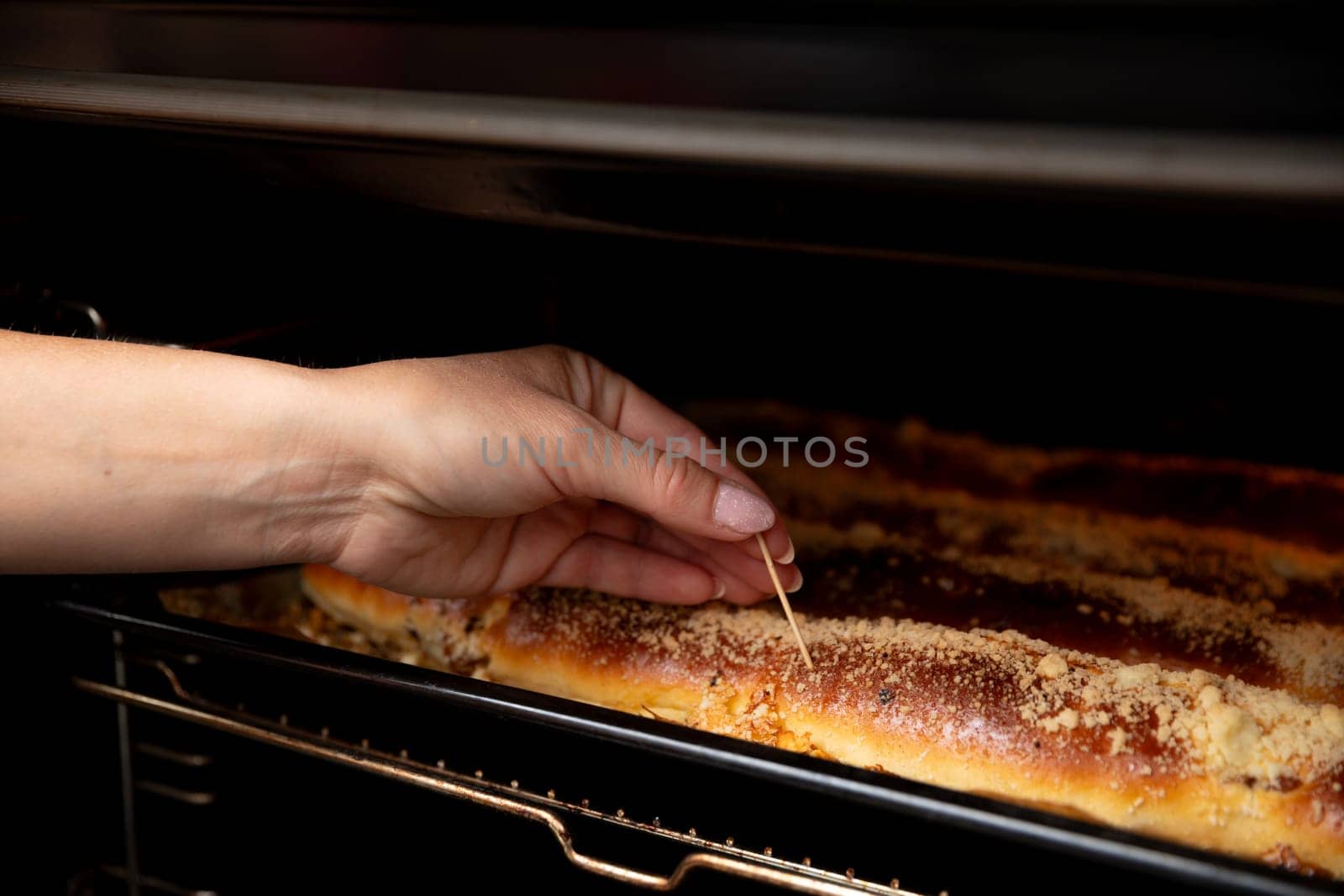 A hand is carefully testing freshly baked bread inside the oven to ensure it achieves perfect doneness and flavor