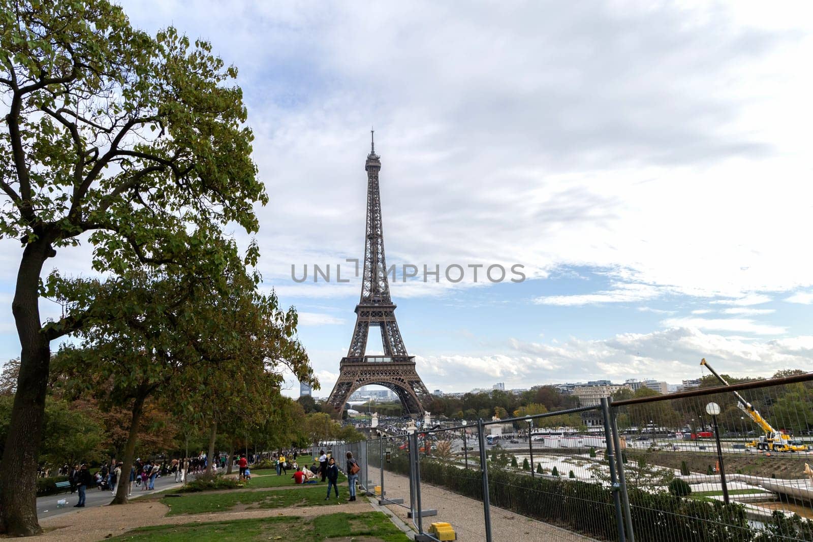 Experience a breathtaking view of the iconic Eiffel Tower perfectly framed by vibrant, colorful trees and a cloudy sky. Paris, France - October 24, 2024