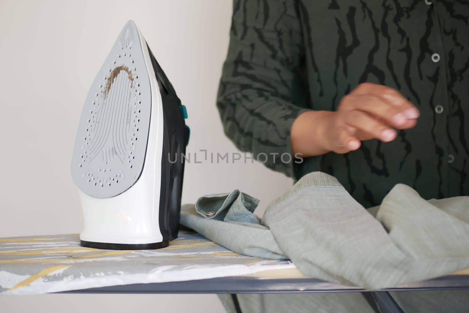 This is a closeup shot depicting a person diligently ironing clothes on an ironing board