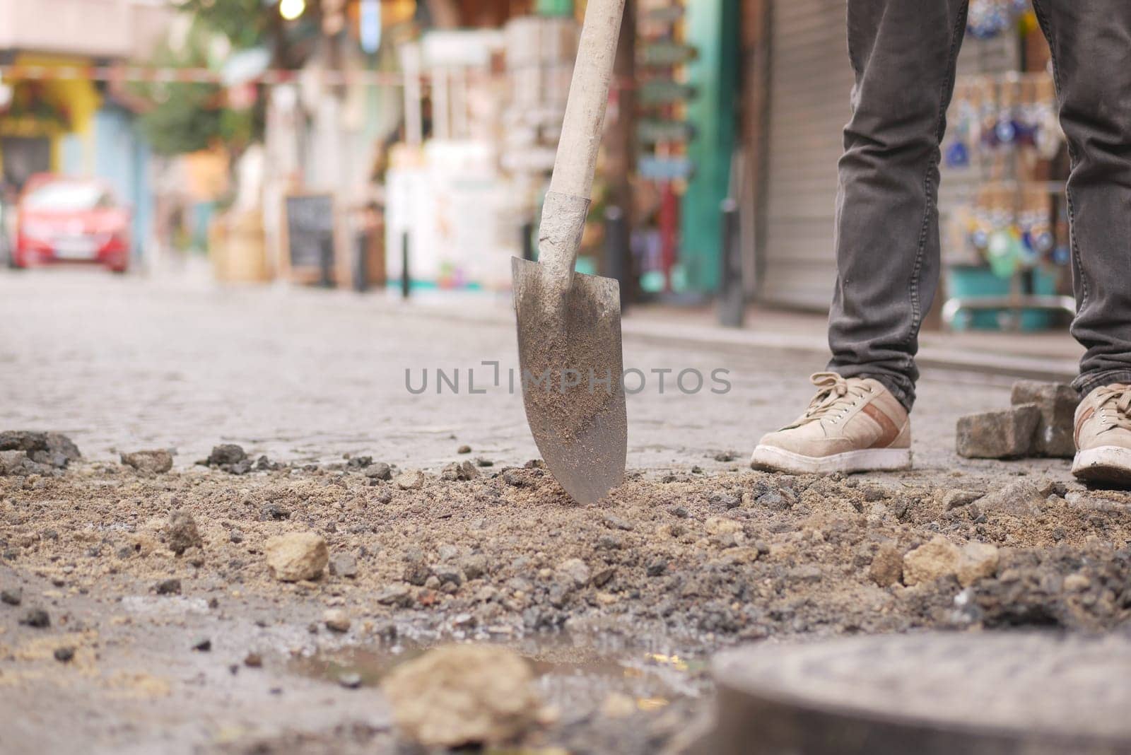 A worker is diligently digging in a busy city street with a sturdy shovel as part of his job