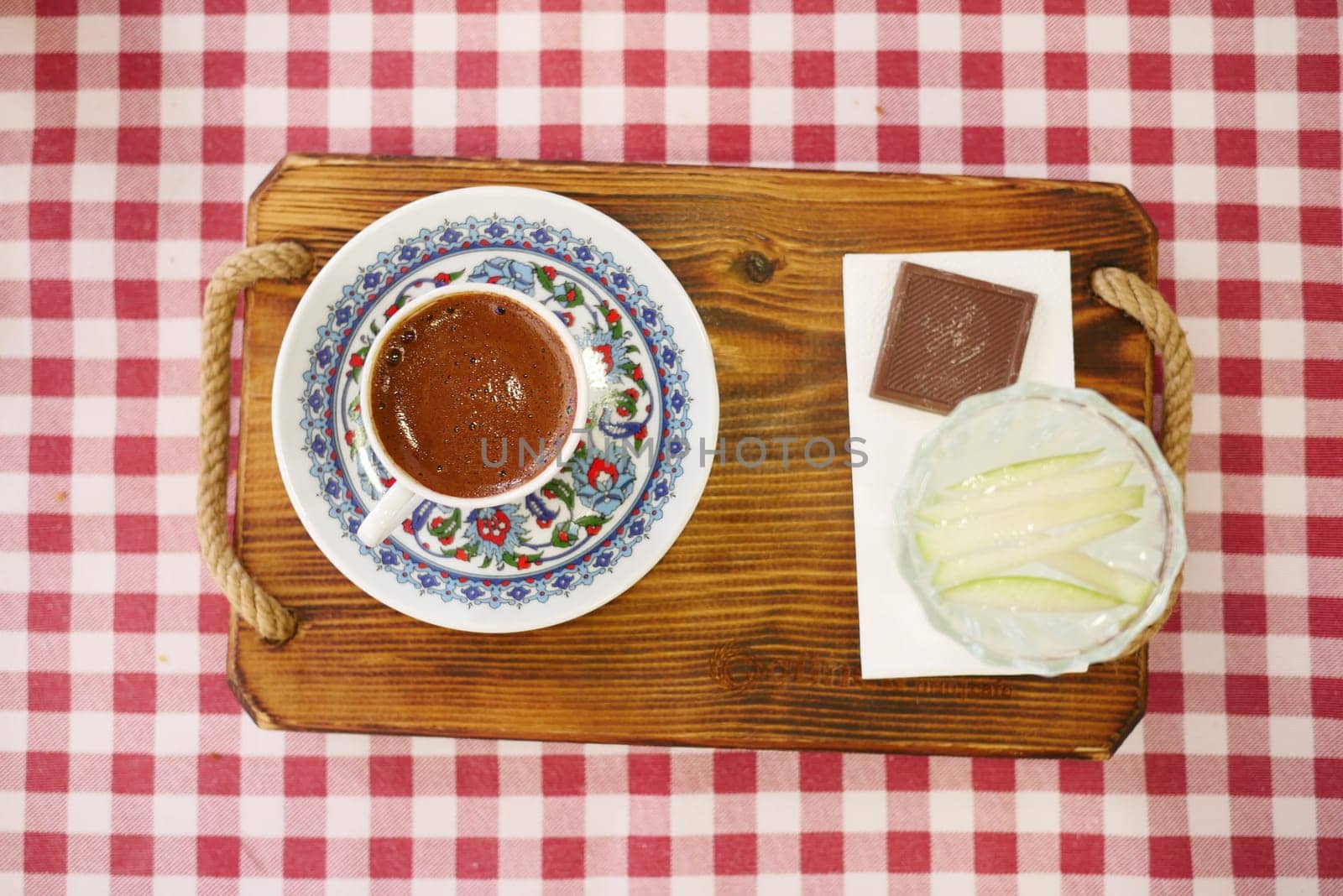 A steaming Turkish coffee served in a traditional floral cup on a checkered tablecloth. Perfect for cultural, culinary, or cozy home-themed projects.
