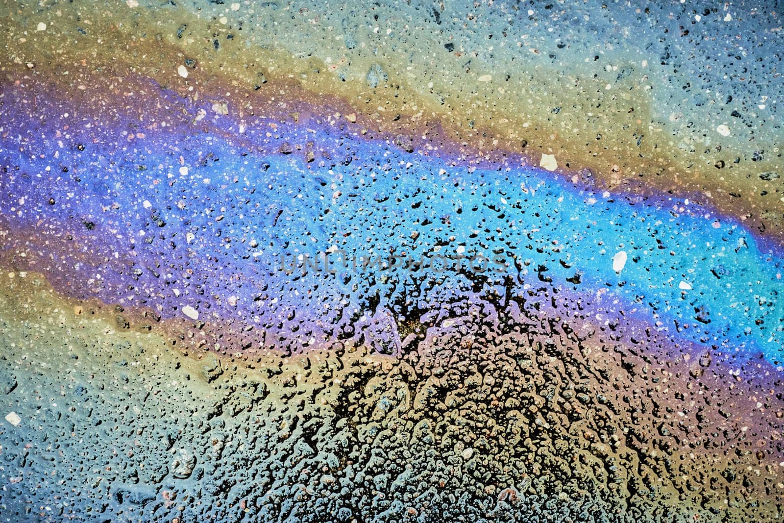 Colorful gasoline spill creating a rainbow effect on asphalt road.