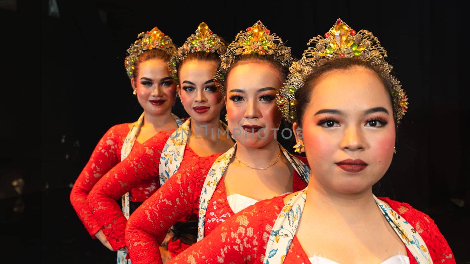 a group of Javanese dancers wearing uniform red costumes creates visual harmony that amazes the audience at night