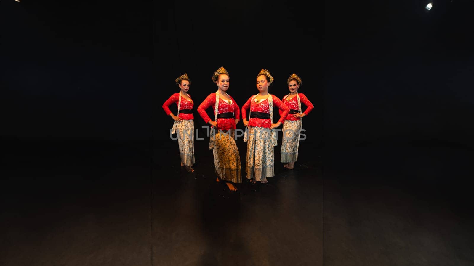 a group of female dancers in red costumes standing in a harmonious and equal position on the stage at night