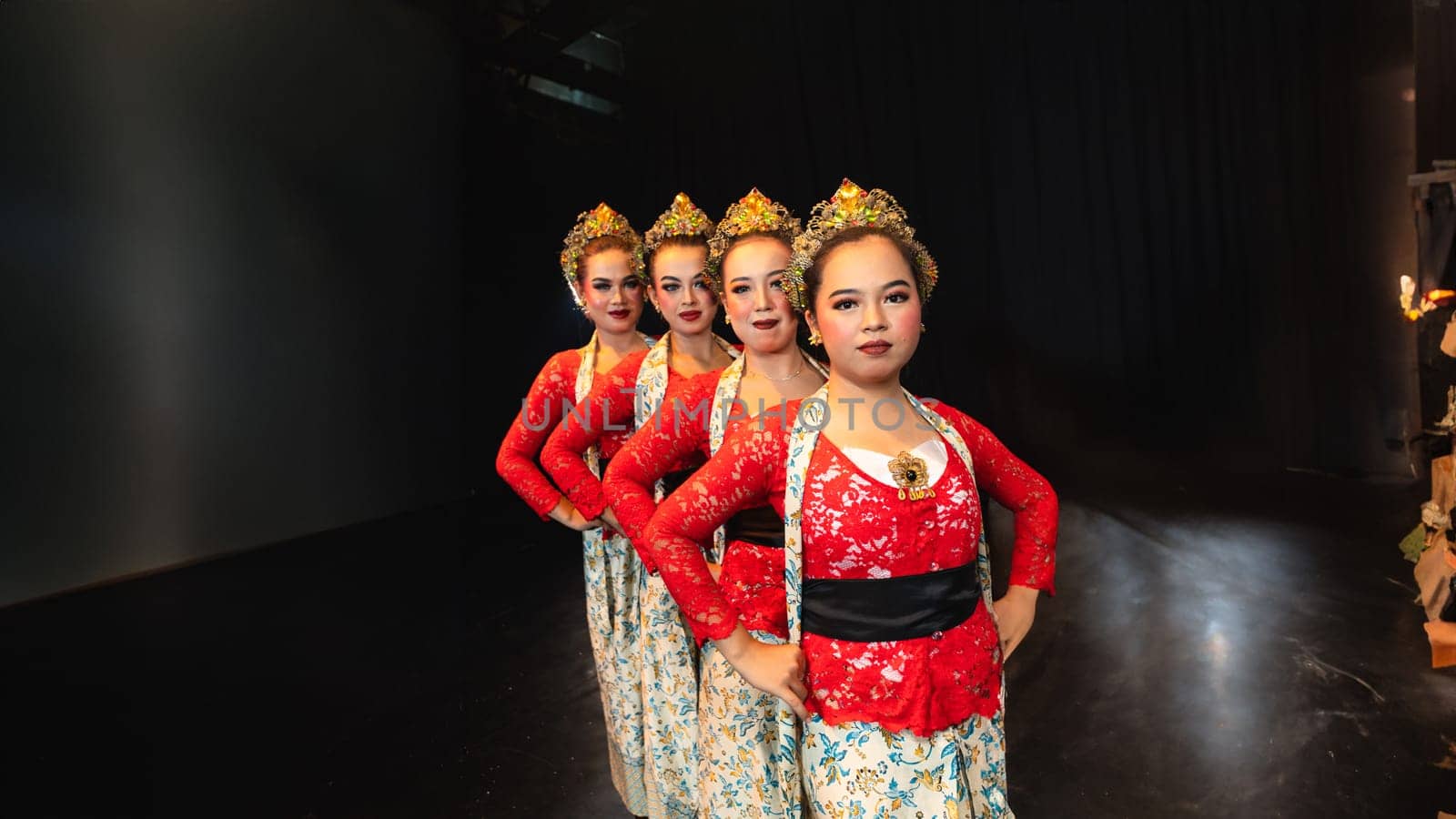 a group of female dancers in red costumes standing in a harmonious and equal position on the stage at night