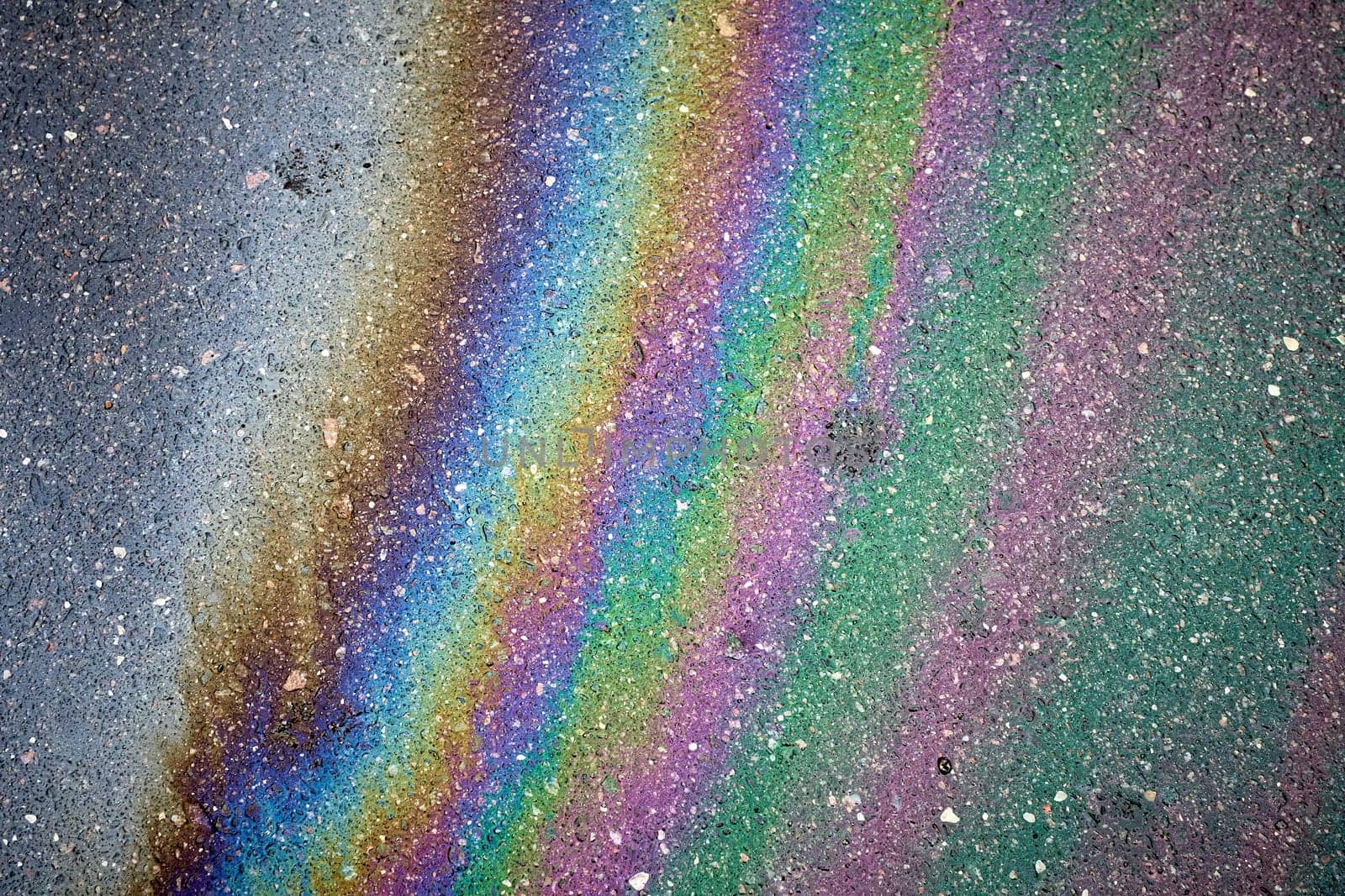 Gasoline rainbow colors creating an oil slick on asphalt road