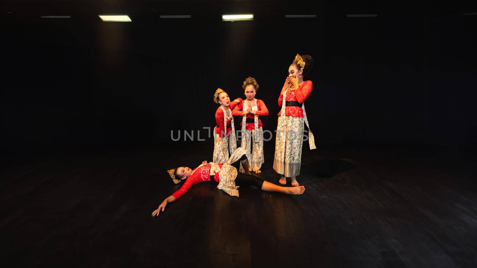a group of traditional Javanese dancers wearing red costumes which provide a dramatic effect on the stage at night