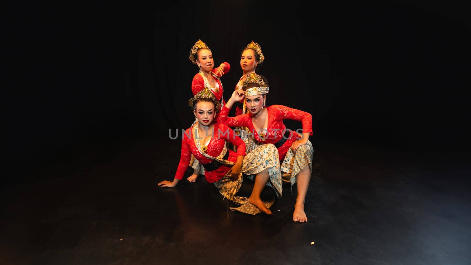 a group of traditional Javanese dancers wearing red costumes which provide a dramatic effect on the stage at night
