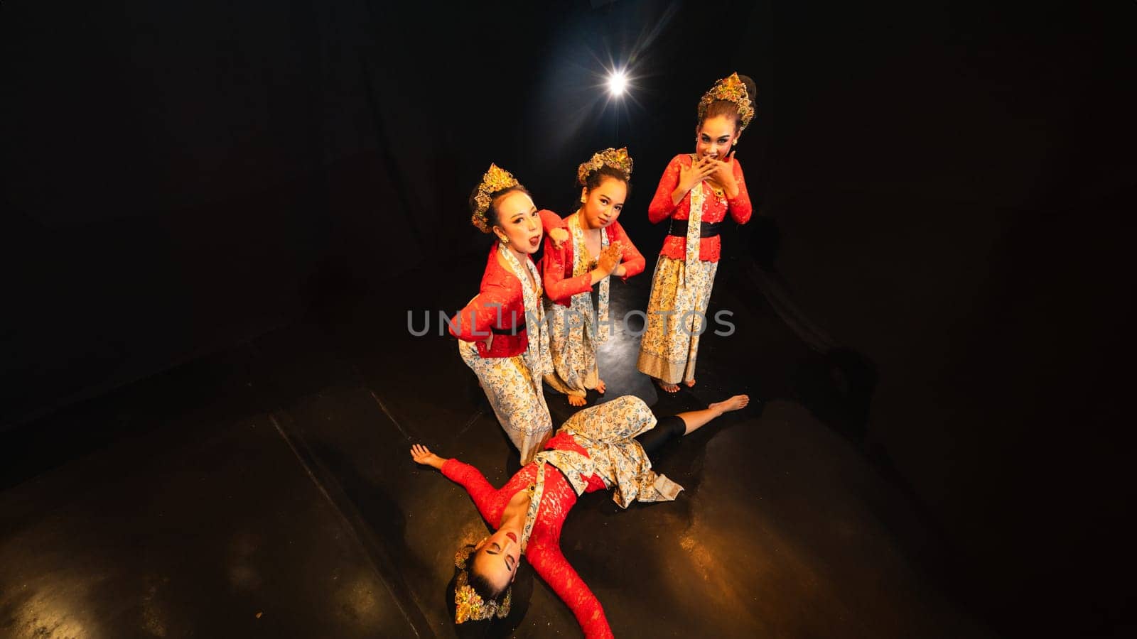 a group of traditional Javanese dancers wearing red costumes which provide a dramatic effect on the stage at night
