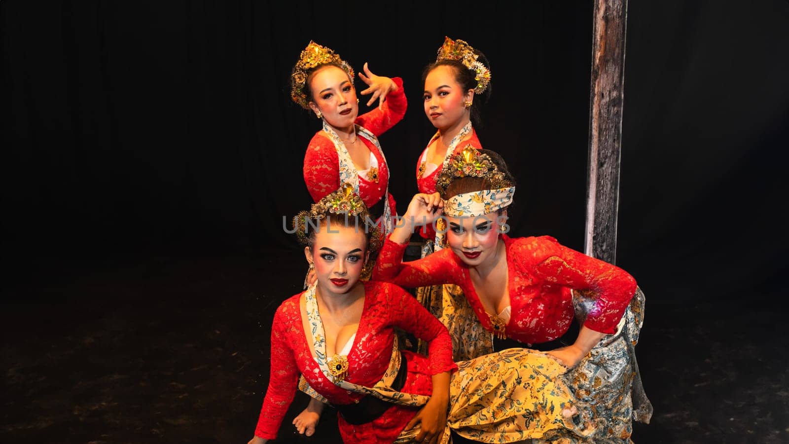 a group of traditional Javanese dancers wearing red costumes which provide a dramatic effect on the stage at night