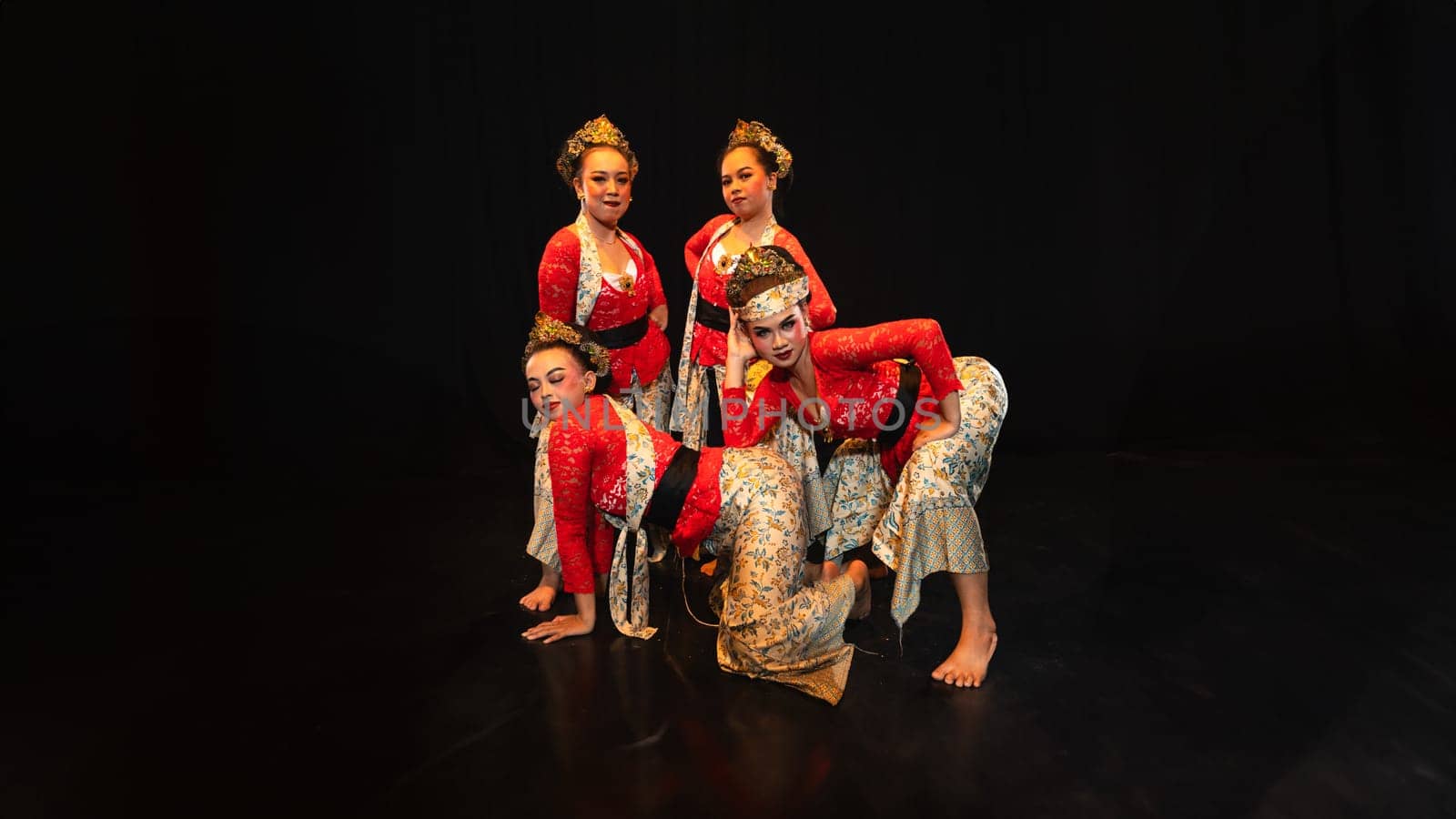 a group of traditional Javanese dancers wearing red costumes which provide a dramatic effect on the stage at night
