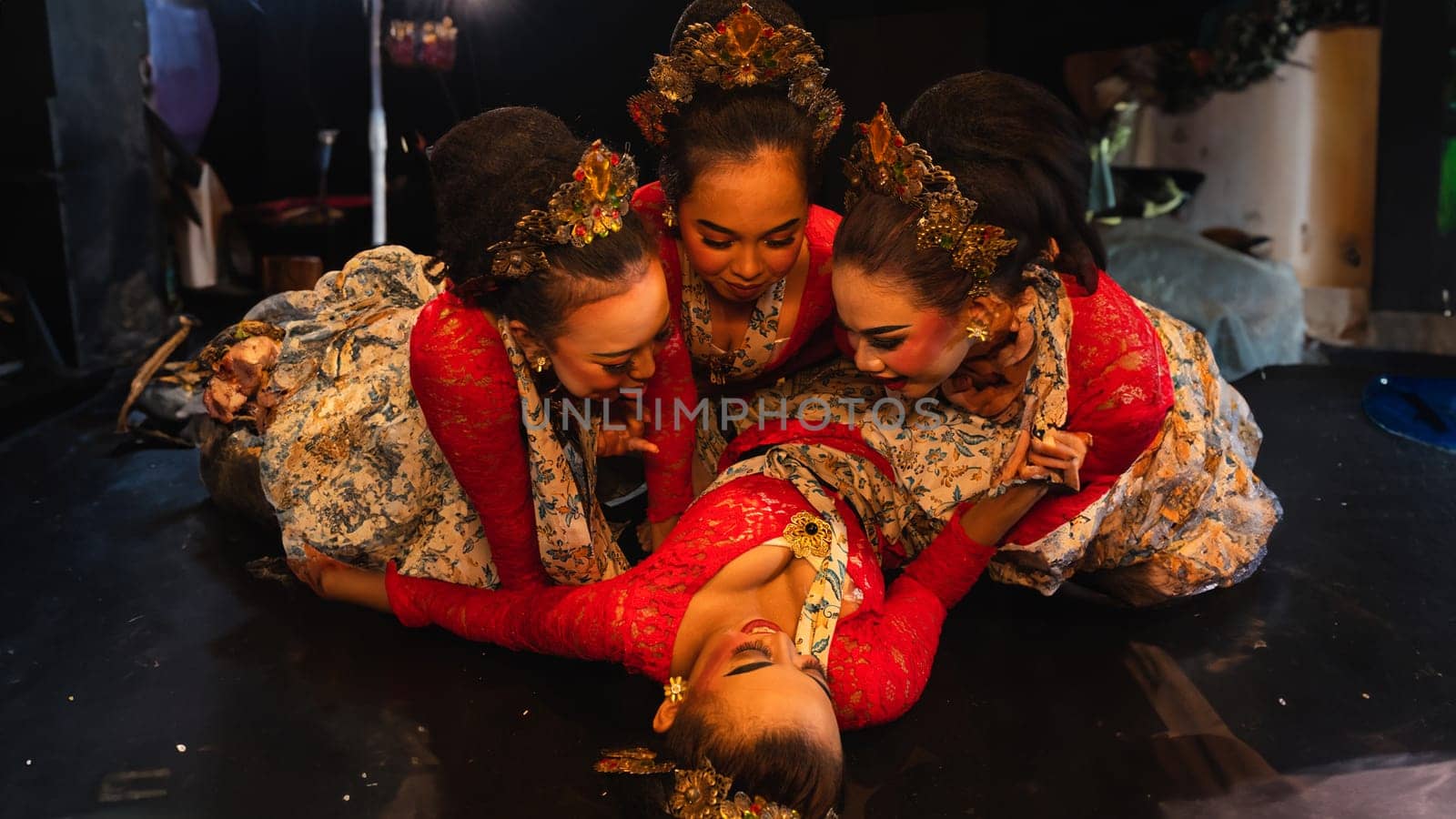 a group of traditional Javanese dancers wearing red costumes which provide a dramatic effect on the stage at night