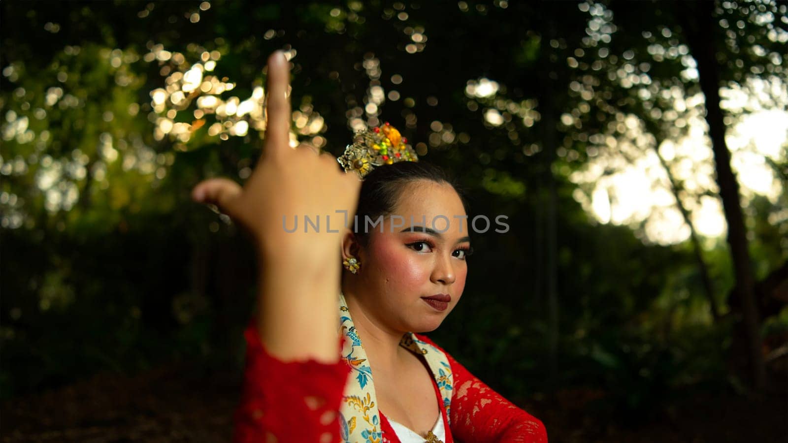 a Javanese dancer wearing a red costume that is thick with legends and religious rituals while in the forest in the afternoon