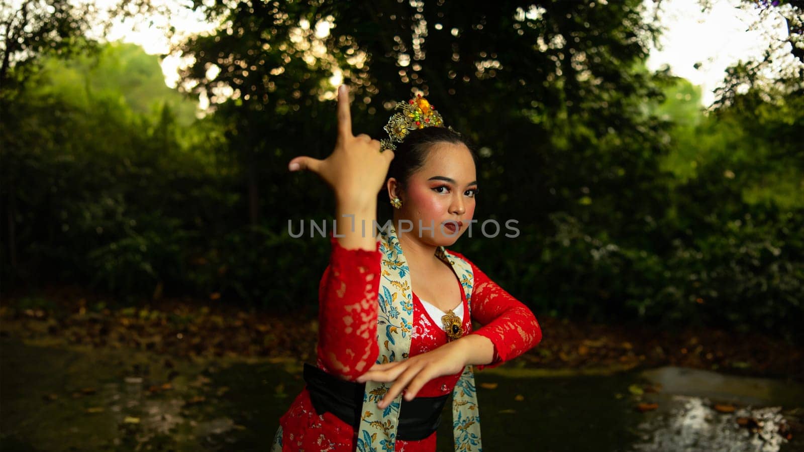 a Javanese dancer wearing a red costume that is thick with legends and religious rituals while in the forest in the afternoon