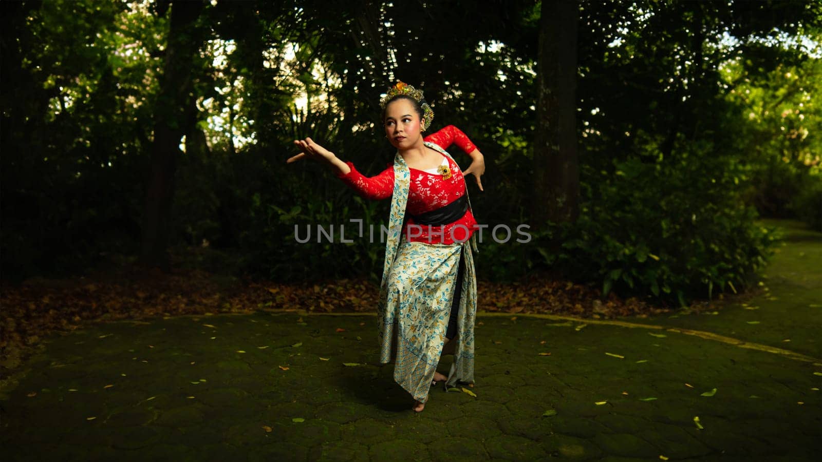 a Javanese dancer wearing a red costume that is thick with legends and religious rituals while in the forest in the afternoon