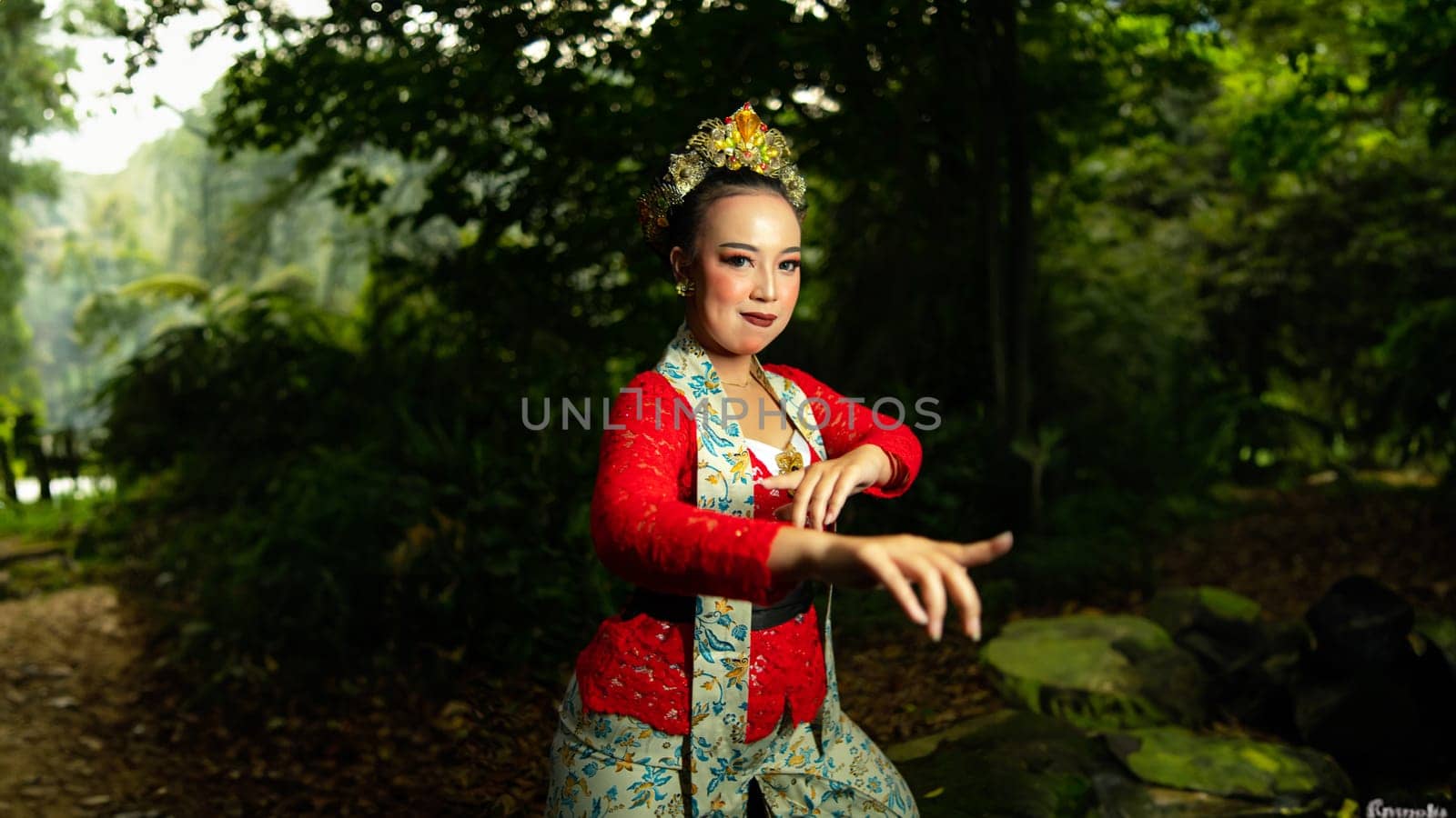a traditional Sundanese dancer wearing a red costume which is the identity of a stunning and impressive dancer when in the forest in the afternoon